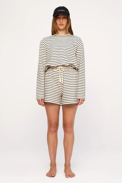 Front view studio photo of a model wearing the Zulu & Zephyr Jersey Sport Short in Black Stripe styled with the matching long-sleeve jersey shirt and black cap.