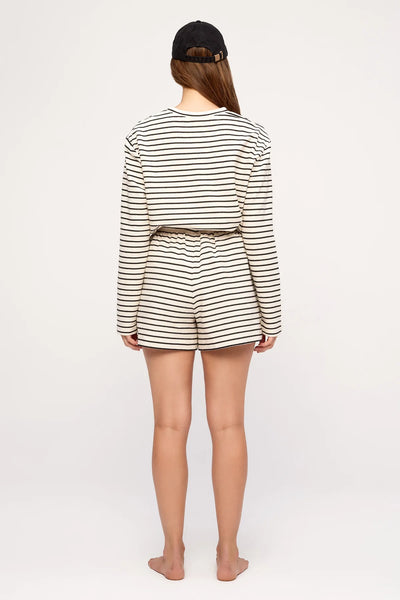 Rear view studio portrait of a model wearing the Zulu & Zephyr Jersey Sport Short in Black Stripe with matching long-sleeve top and black canvas cap.