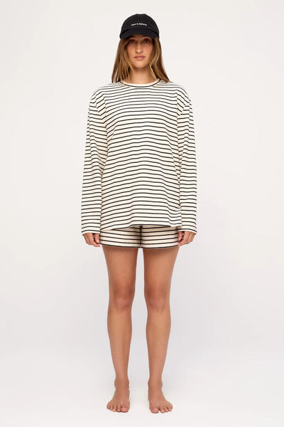 Full-body studio portrait of a model in the Zulu & Zephyr Jersey Long Sleeve Top in Black Stripe and matching striped jersey shorts.