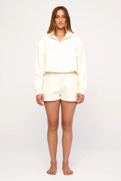 Full-length studio portrait of a model wearing the cream heavyweight Zulu & Zephyr Sport Sweat Shirt Fleece paired with cream sweat shorts.