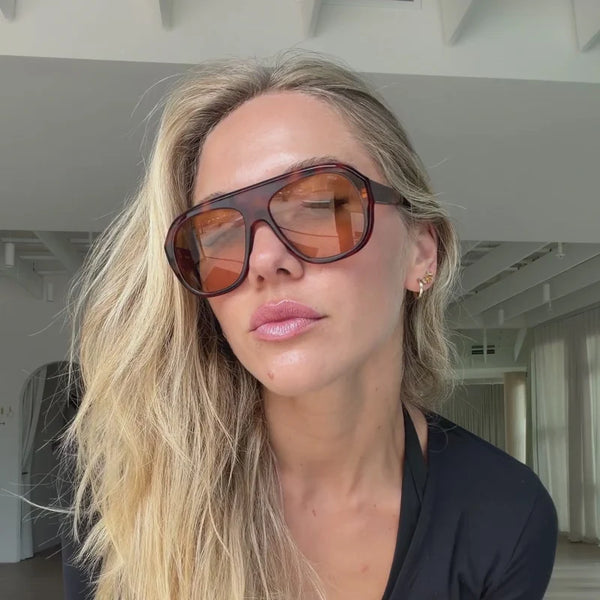 Indoor lifestyle portrait of a blonde model wearing oversized Sito Shades Paloma classic tortoiseshell aviator sunglasses with warm tinted lenses.