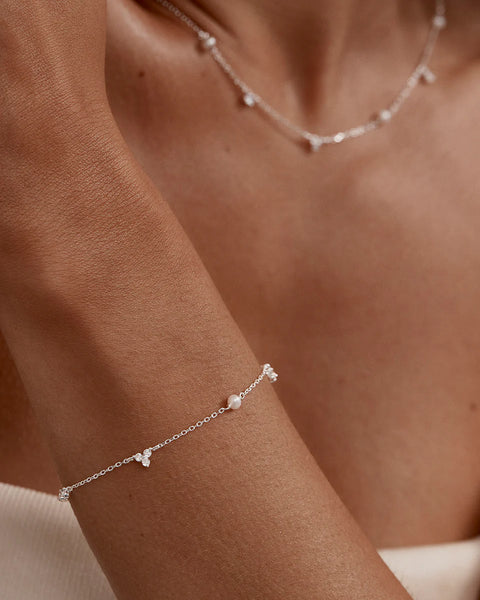 Sterling silver lotus bracelet with freshwater pearls and cubic zirconia. Features an adjustable slider and diamond cut chain.