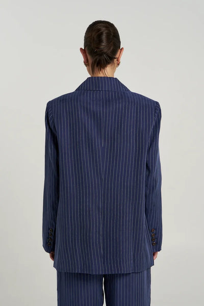 Back view of model wearing the Summi Summi OS Blazer in Navy Pinstripe, displaying button cuff details, central rear seam, and structured hemline.