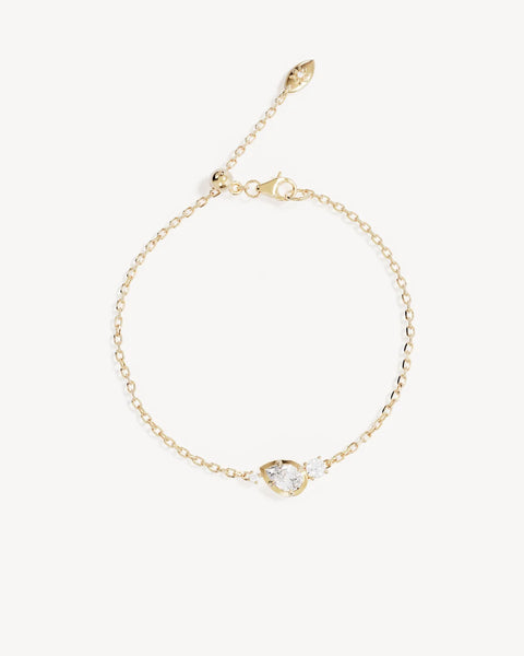 Flat lay studio product shot of the By Charlotte Quiet Radiance Gold Bracelet displaying the adjustable slider ball and lotus pendant drop tag.