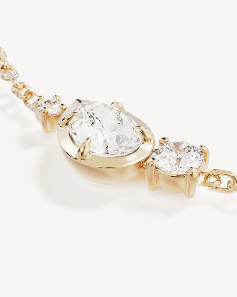 Extreme close-up of the By Charlotte Quiet Radiance Bracelet showing pear and round-cut cubic zirconias in claw and bezel gold settings.