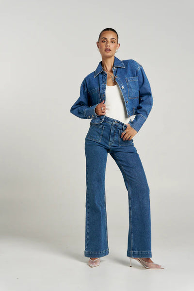 Full-length studio style layout featuring a model layering the figure-hugging Summi Summi Halle Tank in Vanilla under a cropped blue denim jacket, paired with matching wide-leg jeans and white mesh heels.