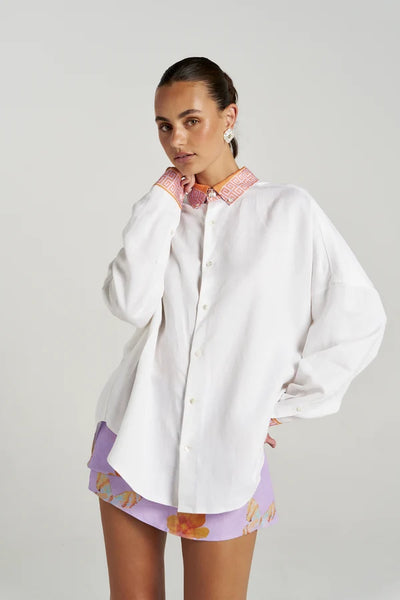 Half-body portrait of a model wearing the Summi Summi Wrap Skirt in Reverie layered beneath an oversized white shirt with matching Reverie trim details.
