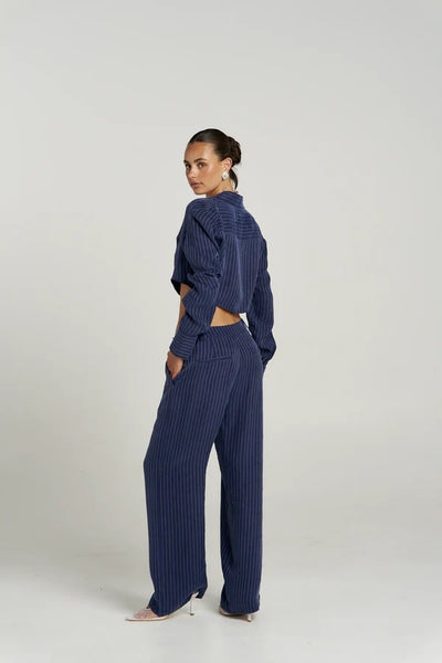 Back detail shot of model wearing the Summi Summi Boss Pant in Navy Pinstripe, displaying the rear waist fit, belt loops, and faux welt pockets.