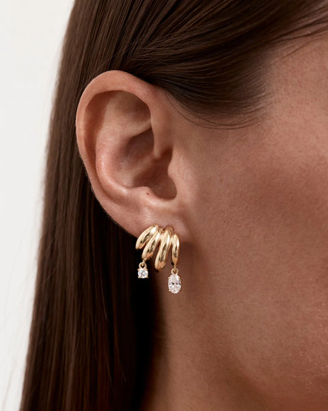 On-model ear profile shot showcasing the By Charlotte In the Stars Illusion Hoop in gold worn in a single lobe piercing to create a stacked hoop look.