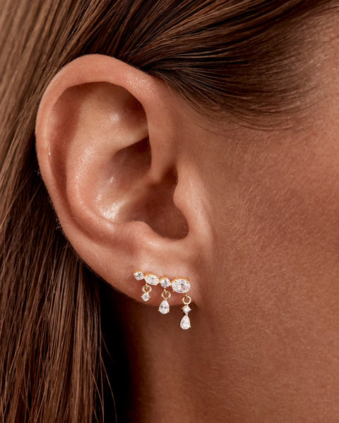 On-model ear profile shot demonstrating the By Charlotte Cosmic Whisper Ear Crawler cascading up the lobe piercing with dangling cubic zirconia stones.