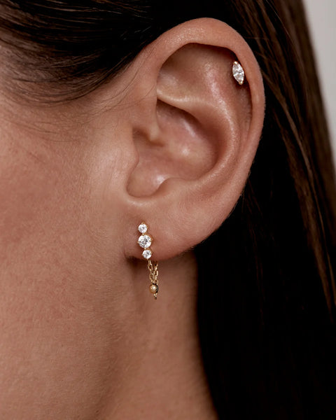 Close-up on-model ear view showing the By Charlotte In the Stars Chain Huggie Earring in 18k gold vermeil worn in a lobe piercing.