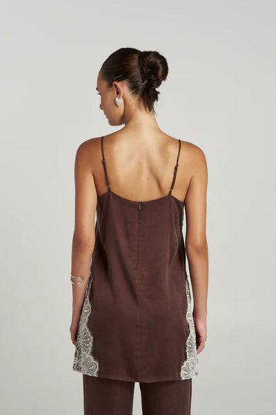 A rear studio view of the model wearing the espresso brown Florence Shift Top, emphasizing the smooth back tailoring, fine adjustable shoulder straps, and a clean concealed center-back zip closure.