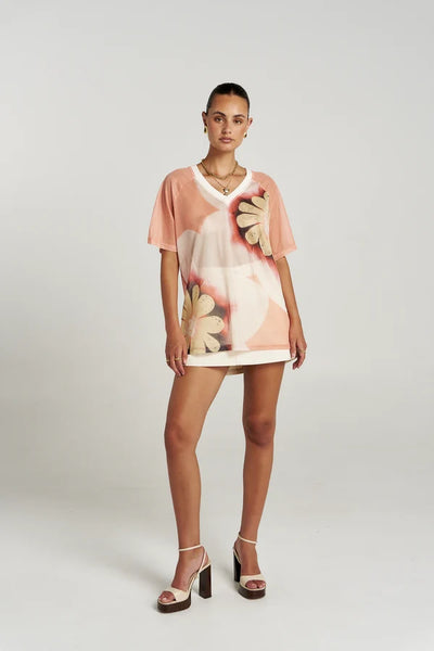 Full-length studio shot of a model wearing the oversized Summi Summi Harlequin Tee in Harlequin, paired with a white skirt and platform heels.