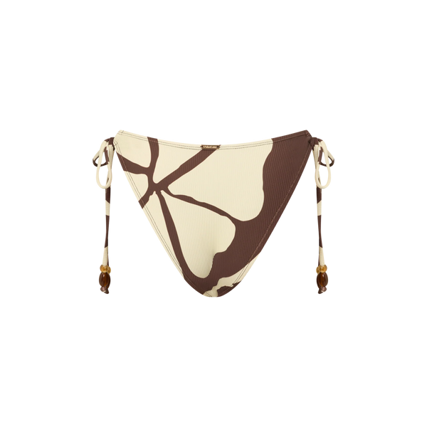 A front-on studio product shot of the model wearing the Ibisco floral string bikini set, detailing the fit of the adjustable loop side ties and the placement of the abstract brown hibiscus motifs against the warm cream ribbed fabric.