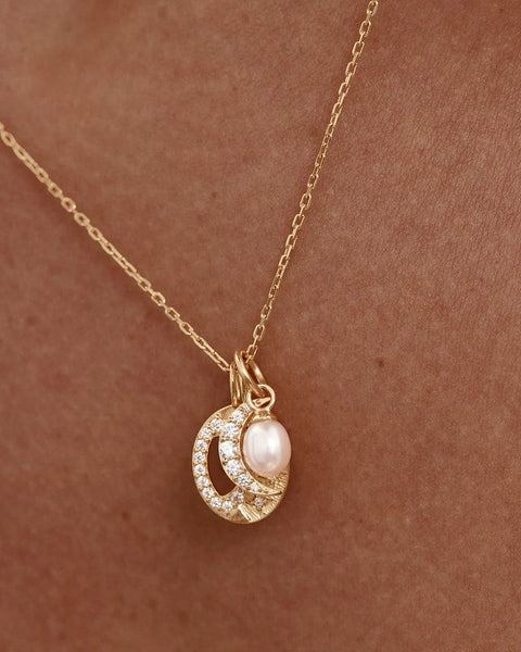 18k gold plated necklace featuring a crystal moon, sun, and freshwater baroque pearl. Includes an adjustable slider and diamond cut chain.