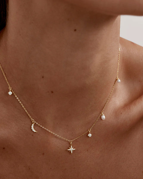 Delicate gold necklace with star and moon pendants.