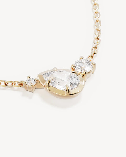 Macro product view of the By Charlotte Quiet Radiance Necklace pendant in 18k gold vermeil, featuring claw-set round and bezel-set pear cubic zirconias on a diamond-cut cable chain.