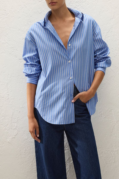 Mid-section shot of a model wearing the Faithfull The Brand En Vau Shirt in Joao Stripe Azulejo Blue, showing the spread collar, front button closure, and vertical blue and white stripe pattern.