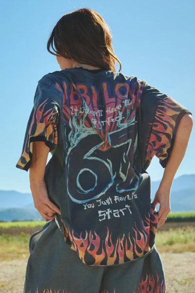 A full-length studio product shot from the back on a model wearing the Flaming Prism Tee, showcasing the continuous cosmic flame artwork and large retro graphic layout that spans across the entire upper back panel.