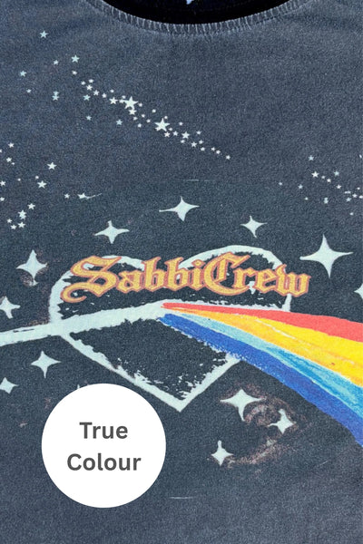 A flat-lay photograph of the Very Oversized Flaming Prism Tee in vintage-washed black charcoal. The t-shirt is laid flat against a white background, showcasing its broad boxy silhouette, slouchy short sleeves, and the vivid retro rock-tour graphic front print featuring cosmic prism artwork, colorful rainbow rays, and bold typography.