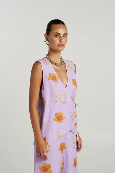Three-quarter studio view of a model in the Summi Summi Tie Front Vest in Reverie, showcasing the overlapping asymmetric front wrap detail and side tie accent.
