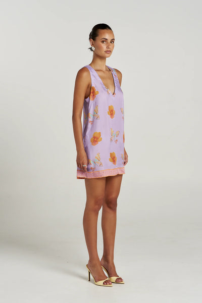 Three-quarter side view of a model in the sleeveless Summi Summi V Shift Dress in Reverie cupro-viscose fabric paired with yellow mule heels.