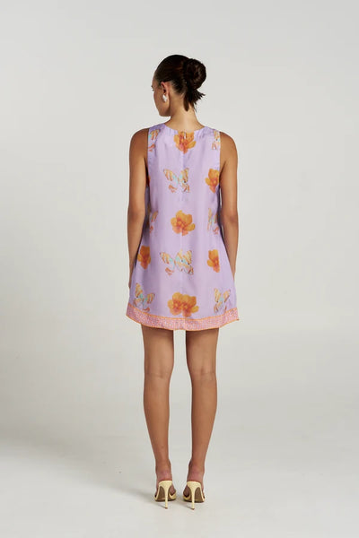 Full-length back view of a model wearing the relaxed-fit Summi Summi V Shift Dress in Reverie showing the rear silhouette and geometric border detail at the hem.