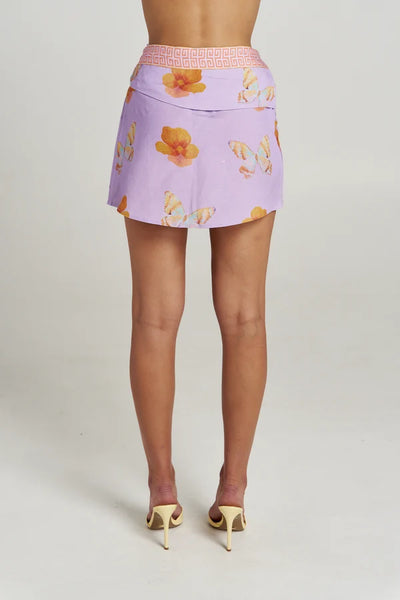Back view of a model in the Summi Summi Wrap Skirt in Reverie showing the geometric trim waistband and butterfly floral print layout.