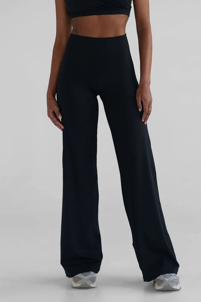 A front view studio shot from the waist down of a model wearing the LEELO Sculpt Wide Leg Pants in classic black. The framing highlights the smooth, no-front-seam design and the secure, seamless high waistband designed for comfortable tummy control.