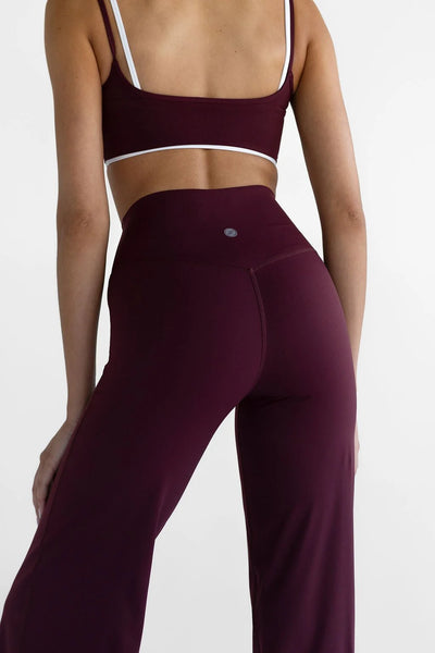 Close-up back view of the Leelo Sculpt Wide Leg Pants in Cherry Cola, showing the contoured rear seam detailing and silver silicone logo on the waistband.