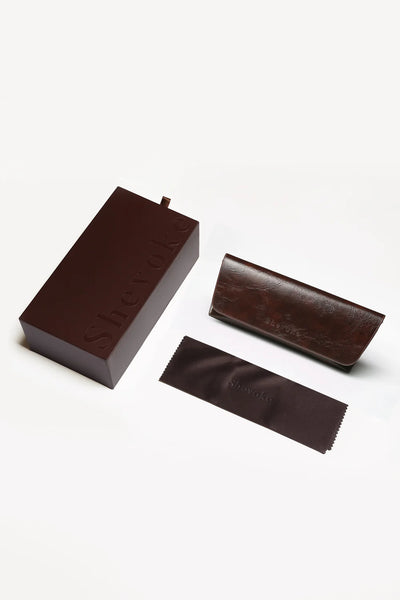 SHEVOKE eyewear luxury brown packaging set featuring a hard box, textured leather protective case, and branded cleaning cloth.