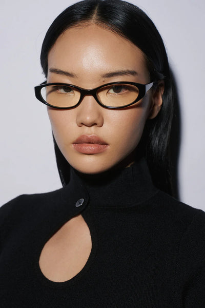 Direct front studio portrait of a female model wearing the black SHEVOKE Silon oval-rectangular frames with yellow-tinted transition lenses.