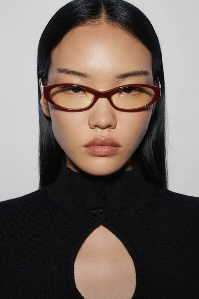 Front portrait of a model wearing SHEVOKE Silon maroon oval-rectangular frames with blue light blocking lenses and a black keyhole top.
