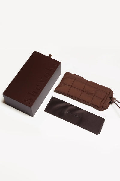 Complete packaging display showing the SHEVOKE branded brown hard box, quilted drawstring soft case, and dark brown cleaning cloth.