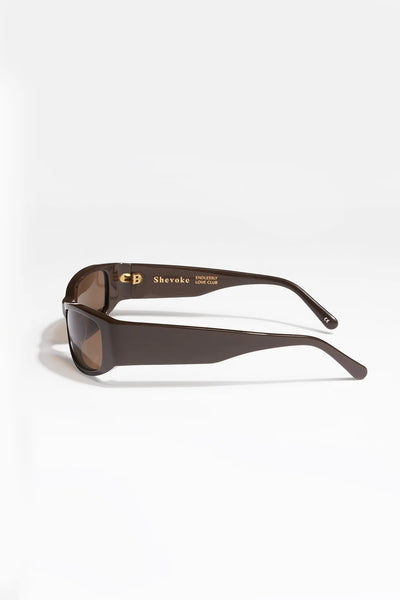 Product shot of the SHEVOKE x Endlessly Love Club Jen 002 brown sunglasses from the side, revealing gold interior arm branding and hardware details.