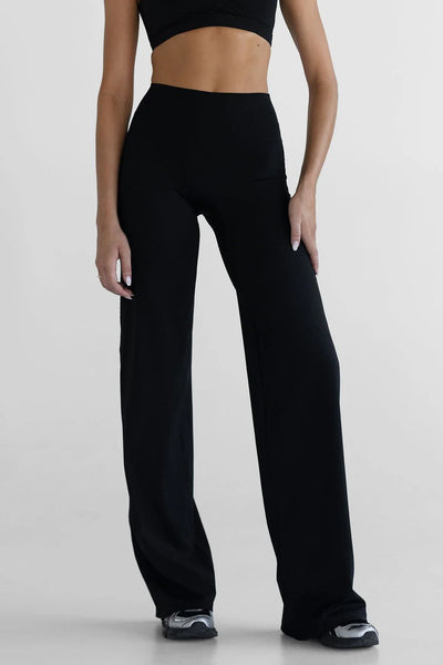 A side-profile studio shot isolating the black activewear wide-leg pants on a model, showcasing the clean lines of the premium stitching, the high-waisted design, and the long, elegant drape of the 36-inch inseam.