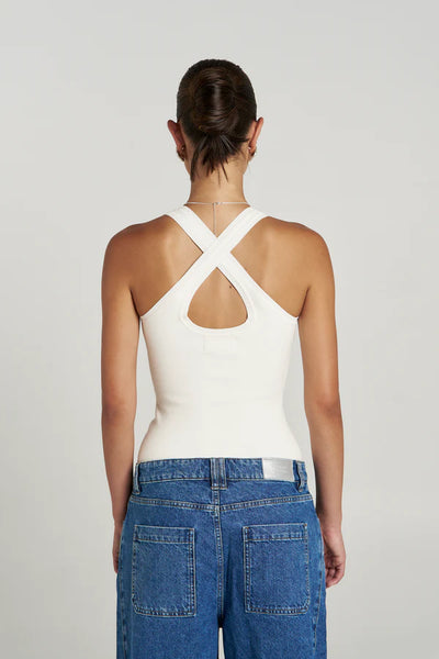 A full studio back view of the model showcasing the symmetrical criss-cross straps and figure-hugging fit of the Vanilla Halle Tank, tucked into low-rise blue denim.